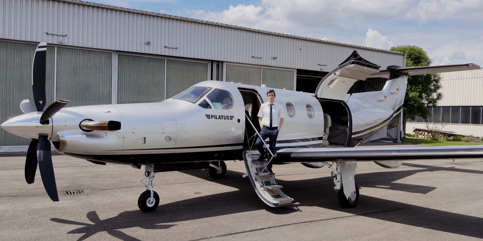 Tim Hittinger sulla scaletta d’imbarco di un Pilatus PC-12, davanti a un hangar.